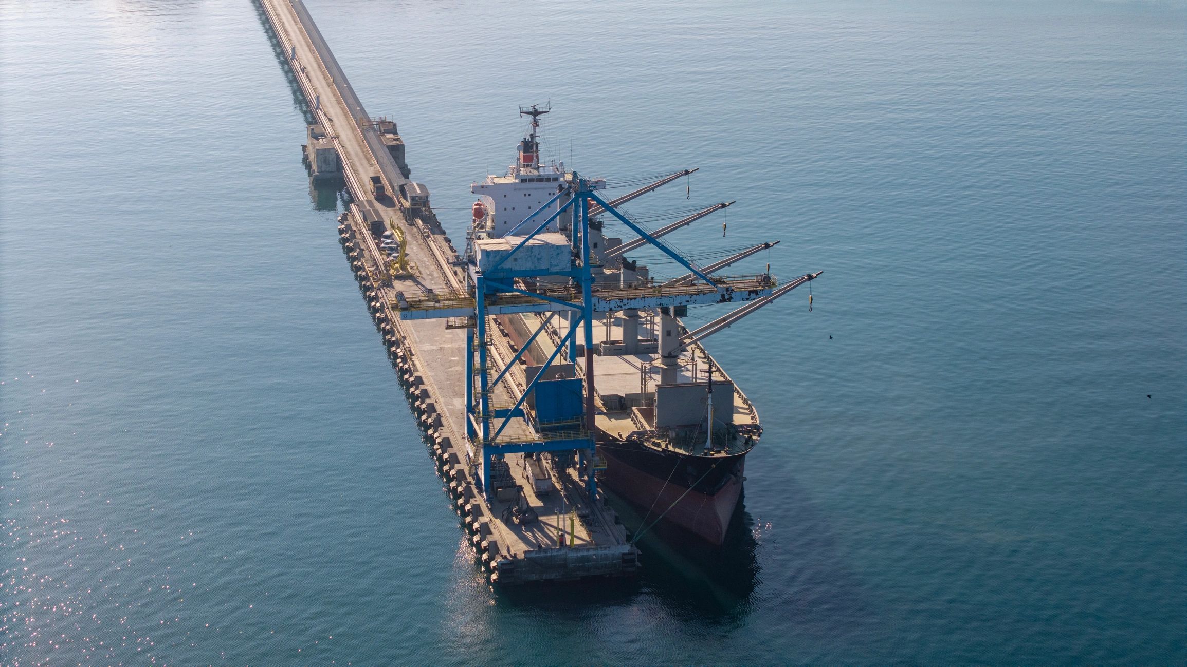 Vista aérea de un buque de carga siendo atendido en un muelle industrial