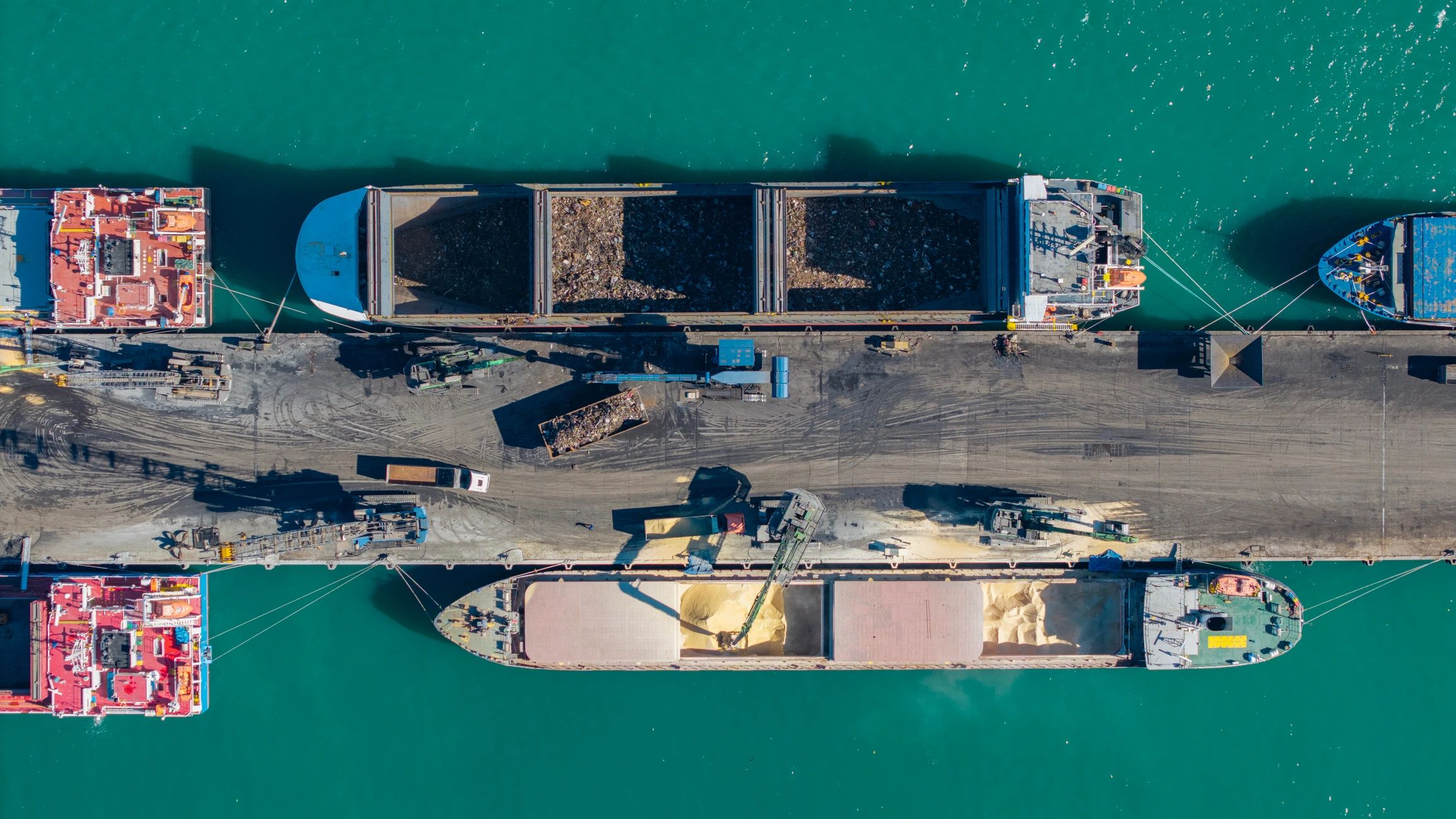 Industrial cargo ships loading grain and materials at busy commercial harbor