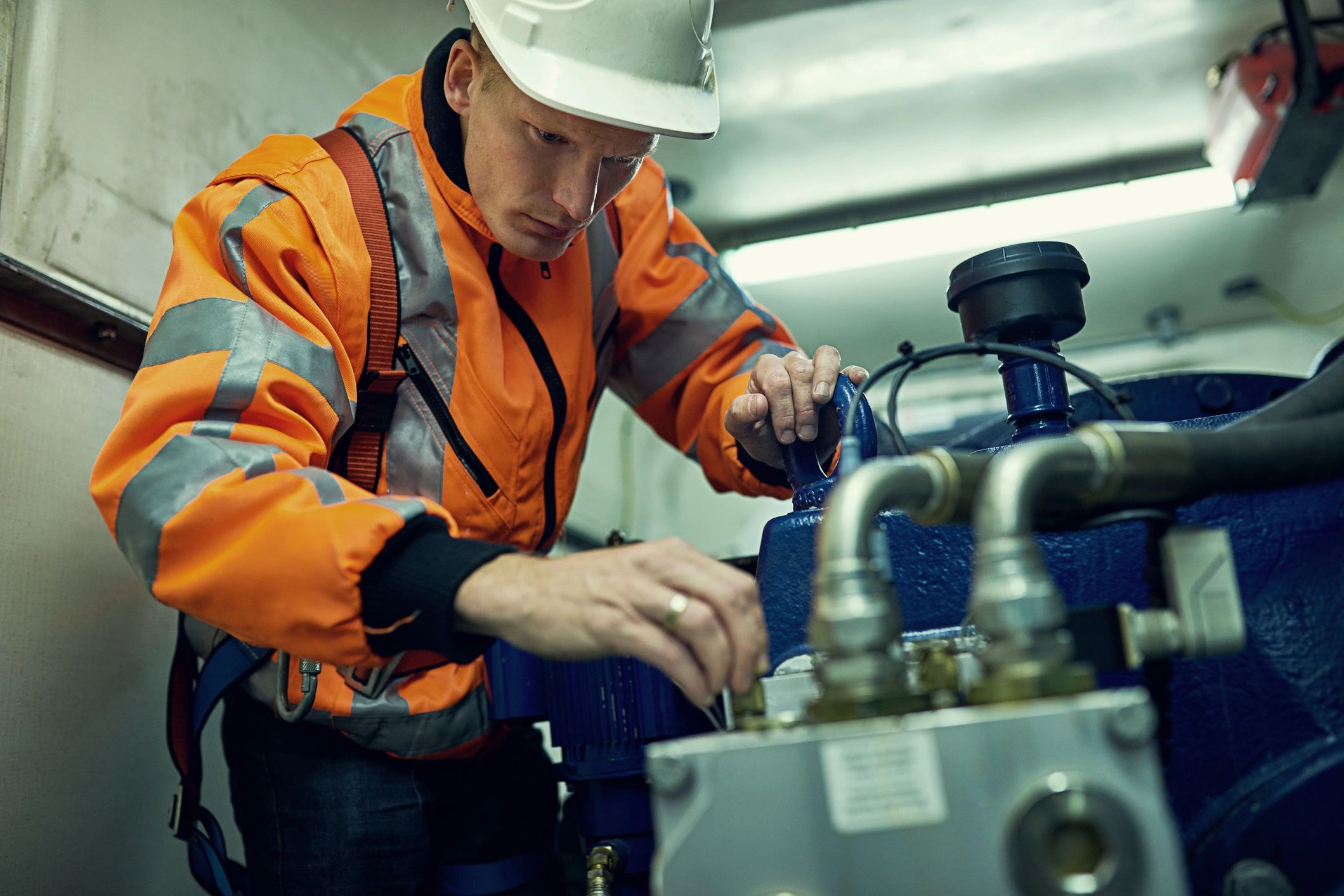 Shot of a young engineer working with complicated machinery while wearing safety gear